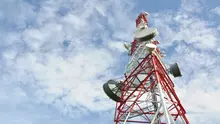 Biało-czerwony maszt telekomunikacyjny na tle nieba z zainstalowanymi radioliniami